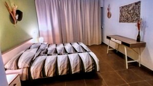 A bedroom with a bed, a desk, a chair, a wall-mounted artwork, and a curtain. - Apartment by the Beach in Dalmatia (Šibenik)