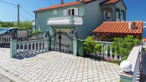 Un bâtiment à deux étages, doté d’un toit en tuiles, d’une entrée fermée par un portail et d’une allée pavée.