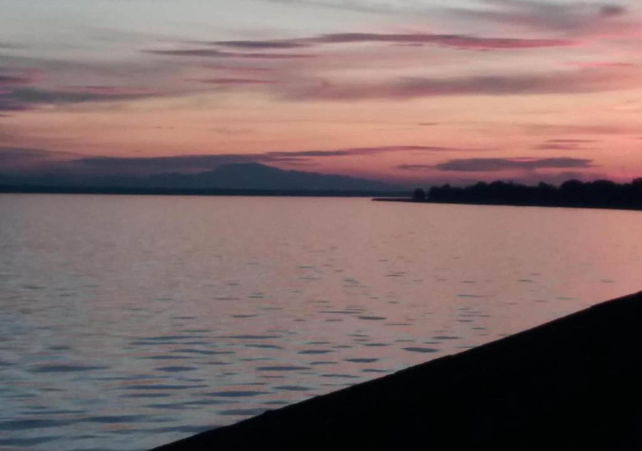 Une étendue d'eau calme qui reflète le ciel au coucher du soleil.