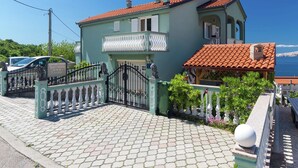 Un bâtiment à deux étages, doté d’un toit en tuiles, d’une entrée fermée par un portail et offrant une vue sur la mer.