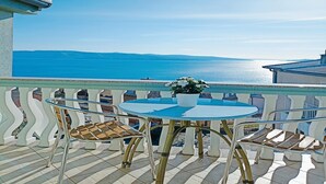 Une terrasse avec vue sur la mer, une table ronde et des chaises.