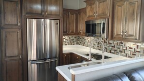 Een moderne keuken met roestvrijstalen apparatuur, houten kastjes, een wit aanrecht en een inbouwspoelbak.