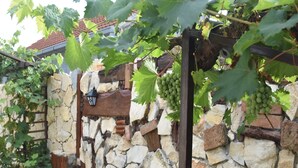 Un mur de pierre avec une porte en bois et un poteau en bois surmonté d’une lanterne.