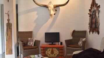 A living room with two wicker chairs, a television, and a wall-mounted bull skull.
