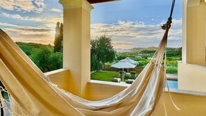 Uma rede sob uma pérgula com vista para uma paisagem exuberante e uma piscina.