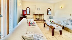Uma sala de estar com sofá, mesa de centro, lareira e televisão.