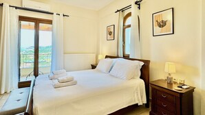 Quarto de hotel com cama, mesa de cabeceira e vista para o exterior.