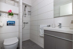 A modern bathroom with a toilet, shower, and vanity.