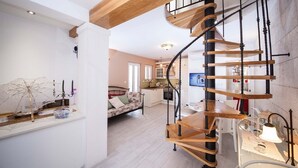 Ein großzügiger Wohnbereich mit einer Holztreppe, einem Sofa und einem Esstisch.