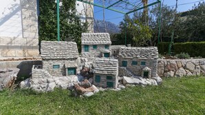 Un modelo de edificios de piedra con ventanas verdes, rodeado de césped y árboles.