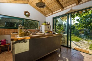 A kitchen with a wooden ceiling, a large window, and a view of a garden.