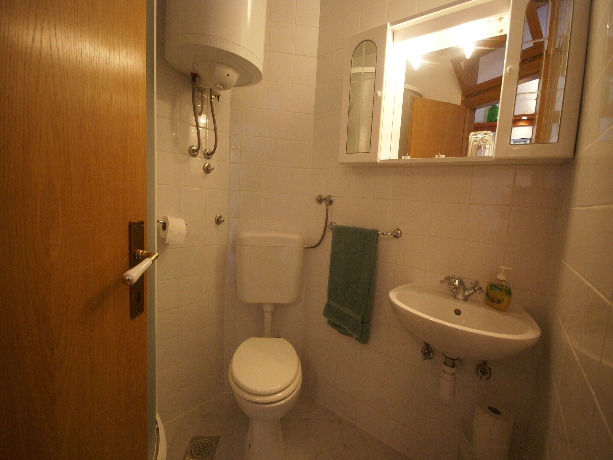 A bathroom with a toilet, sink, and mirror.