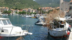 A marina with boats docked, surrounded by traditional buildings and a mountainous backdrop. - Coastal apartment in Vis near sea (Vis)