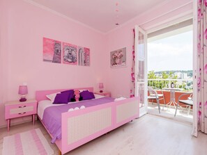 Un dormitorio con decoración rosa y un balcón.