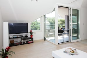 Relax in this stylish living room with a flat-screen TV, sliding glass door to a balcony, and comfortable seating area.