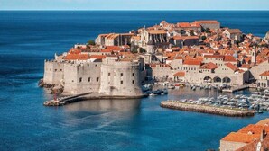 A coastal city with historic architecture, including a prominent castle and fortified walls, surrounded by a marina with boats. - Modern Stay near Cavtat (Močići, Dubrovnik - Konavle Region)