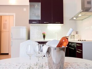 A dining table with a bottle of wine, glasses, and a vase with flowers. - Cozy villa in Ploce with shared pool (Ploce)