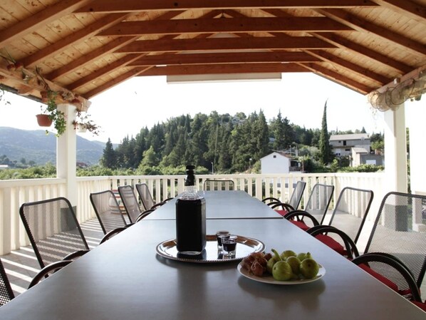 A covered outdoor dining area with a table set for six, a bottle of water, and a plate of fruit. - Cozy villa in Ploce with shared pool (Ploce)
