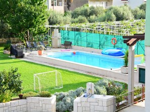 A swimming pool with a safety fence, lounge chairs, and a small garden area. - Cozy villa in Ploce with shared pool (Ploce)