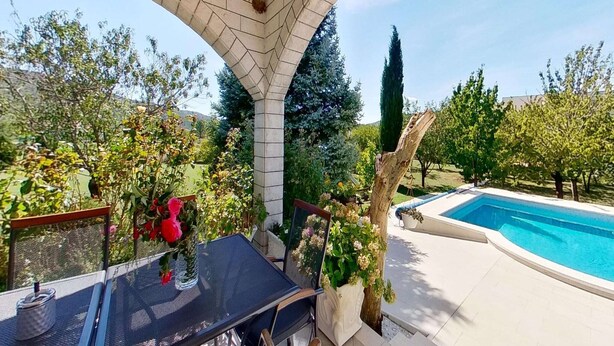 A covered patio area with a pool, outdoor seating, and a view of the surrounding garden and trees. - Beautiful holiday home with private sauna (Neoric)