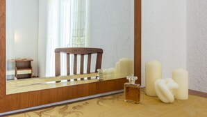 A bathroom with a wooden chair, a mirror, a small table, and several candles.
