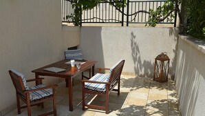 A patio with a wooden table and chairs, a laptop, a glass, and a lantern.