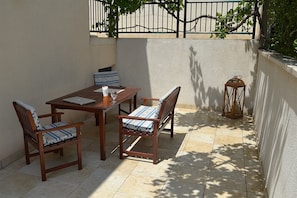 A patio with a wooden table and chairs, a laptop, a glass, and a lantern.
