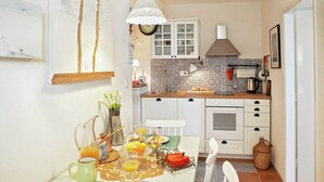 A kitchen with white cabinets, a tiled backsplash, and a hanging light fixture. - Cozy Apartment Brela (Brela)