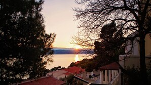 A coastal view with a sunset, houses with red roofs, and a clear sky. - Cozy Apartment Brela (Brela)