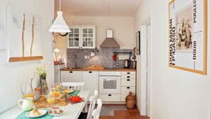 A compact kitchen with white cabinets, a tiled backsplash, and a hanging light fixture. - Cozy Apartment Brela (Brela)