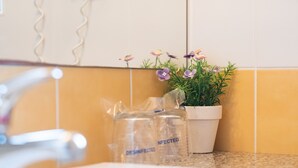 Une salle de bain avec un lavabo, une plante en pot et deux sacs désinfectés.