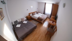 Une chambre d’hôtel avec deux lits, un plancher en bois, une petite table ronde et une armoire.