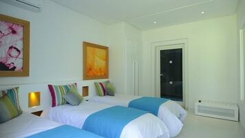 A hotel room with two beds, a large window, and a door.