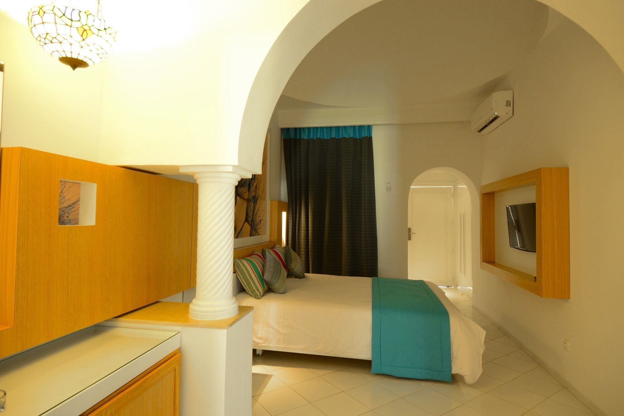 Un dormitorio con cama, escritorio, espejo y puerta.