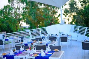 An outdoor dining area with tables set for a meal, surrounded by trees and a covered seating area. - One Resort Aqua Park & Spa (Monastir)