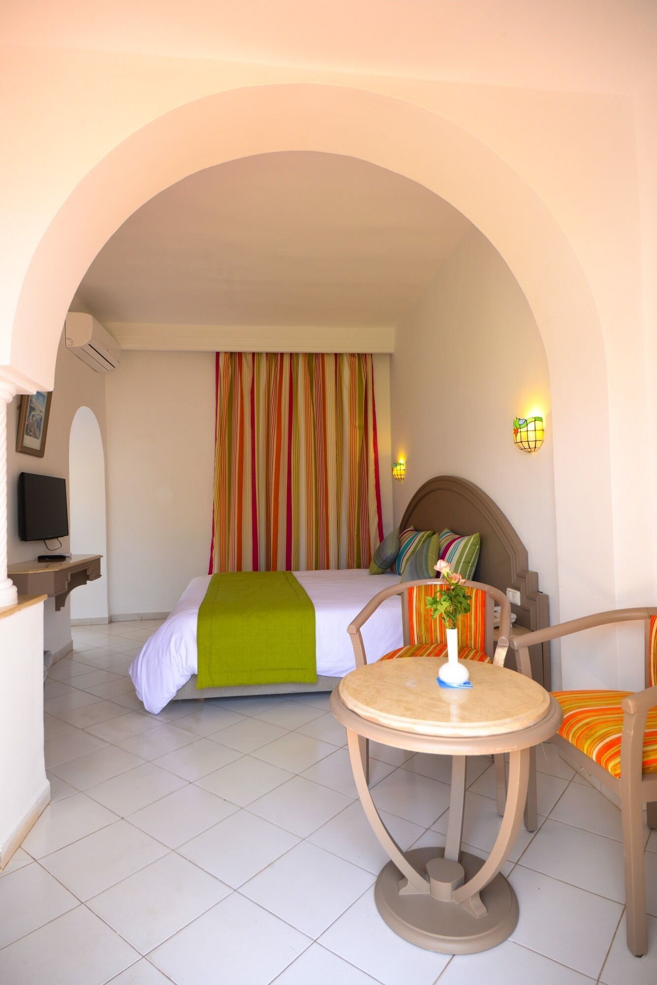 Una habitación de hotel con una cama, televisor, mesa y una silla.