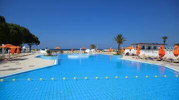 A clear blue pool with yellow floating barriers, surrounded by orange umbrellas and lounge chairs.