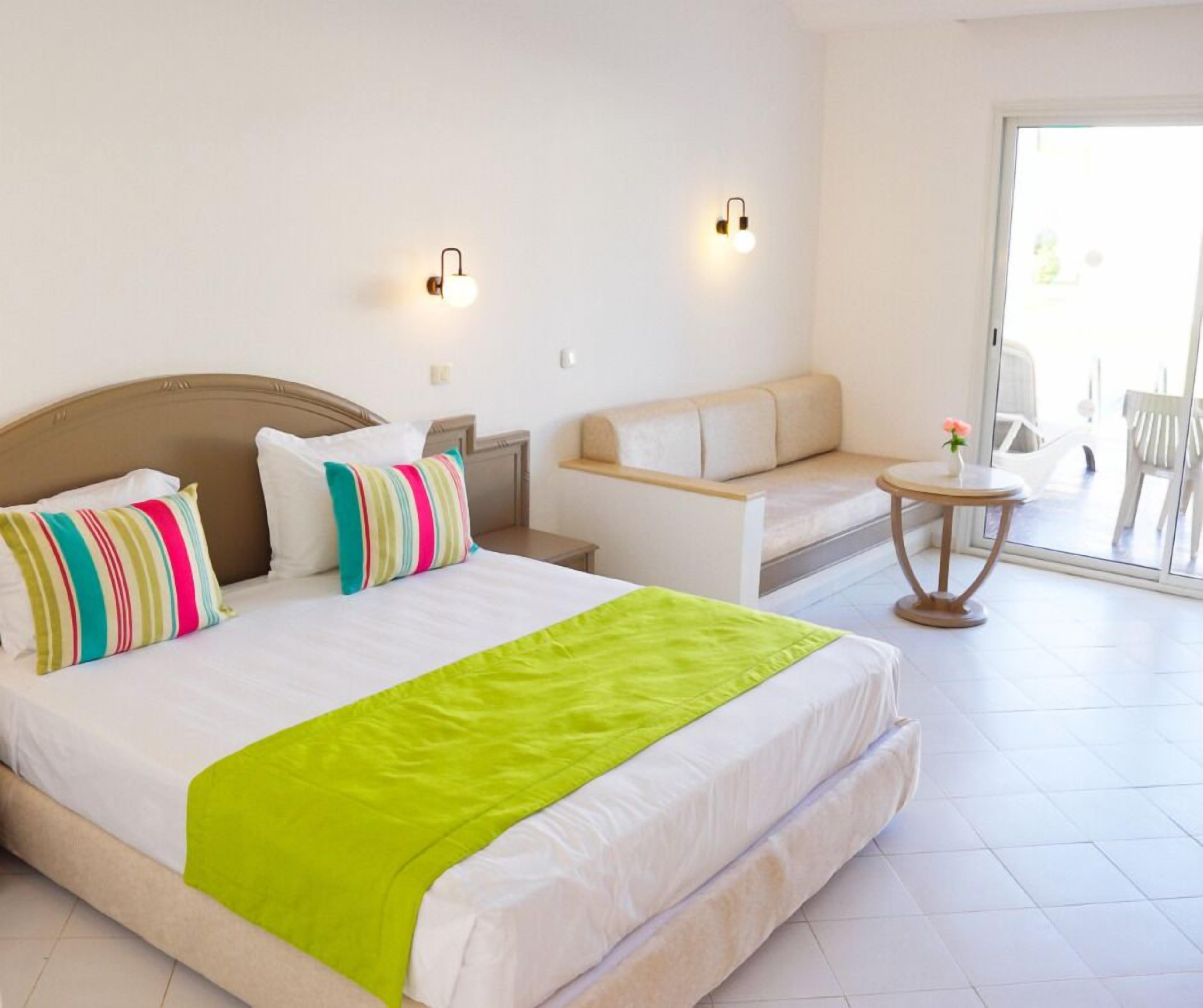 Una habitación de hotel con cama, sofá, una mesita y una silla.