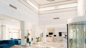 Eine großzügige Lobby mit Marmorboden, blauen Sitzgelegenheiten und einem Empfangstresen.