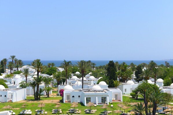 A resort with white dome-roofed buildings, palm trees, and a view of the sea. - One Resort Aqua Park & Spa (Monastir)