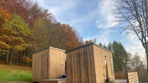 Deux cabanes en bois dotées d’une terrasse, situées dans une zone boisée.