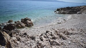 A rocky shoreline with clear water and distant mountains. - Charming Stay in Sveti Križ (Tuhelj)