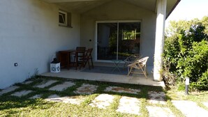 A patio with a table and chairs, a grill, and a sliding glass door leading to a covered area. - Mini villa in the heart of a pretty garden (Porto-Vecchio)