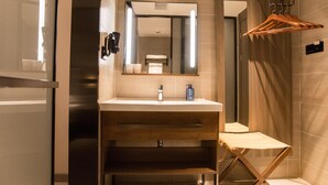 Een moderne badkamer met een houten wastafelmeubel, een spiegel en een handdoekhouder.