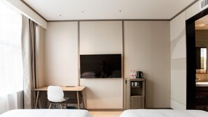 Een hotelkamer met twee bedden, een bureau, een televisie en een minibar.