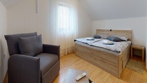 Un dormitorio con una cama, un sofá gris, un cabecero de madera y una mesita de noche pequeña.