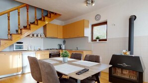 Una cocina moderna con armarios de madera, una mesa de comedor con sillas, un microondas, una estufa y un estufa de leña negra.