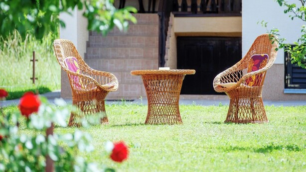 Un jardín con mobiliario de mimbre y chimenea.