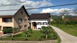 Zona residencial con dos casas, un camino de entrada pavimentado y un césped bien cuidado con árboles.