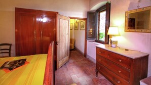 Un dormitorio con un armario de madera, una mesita de noche con lámpara y un espejo en la pared.
